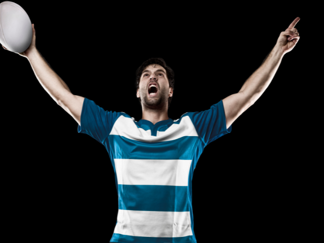 A rugby player in a blue and white striped jersey celebrating with the ball.