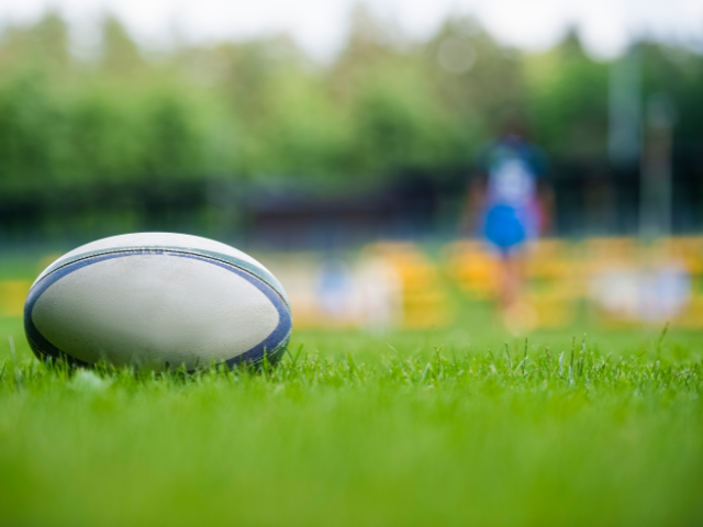 A rugby ball resting on a grassy field during a practice session.