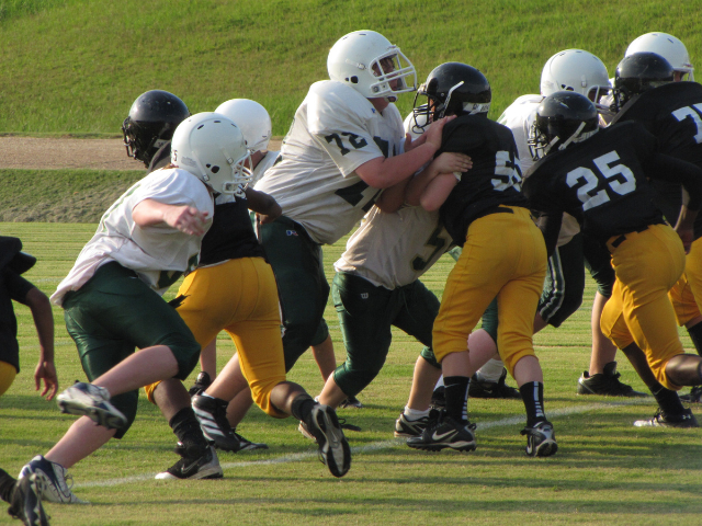 Youth football players tackling during a game.