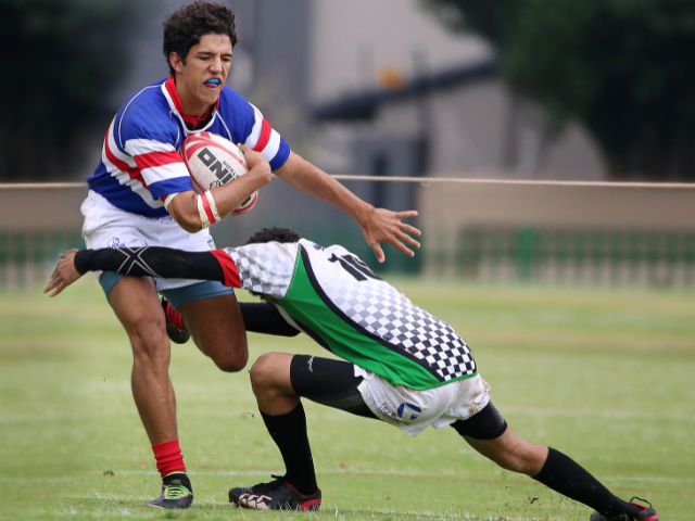 Rugby player attempting to break a tackle while holding the ball.