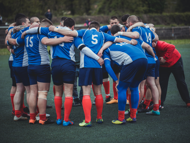 Rugby team huddling together on the field before a match.