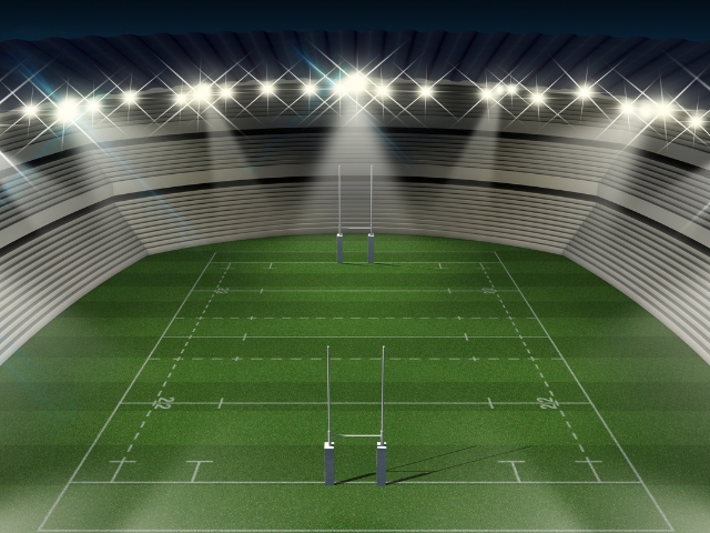  An illuminated rugby stadium at night, showing the playing field with goalposts under bright stadium lights. 