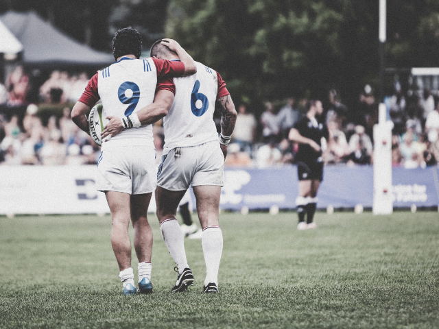 Two rugby players with jerseys numbered 6 and 9 walking together on the field, showing camaraderie.