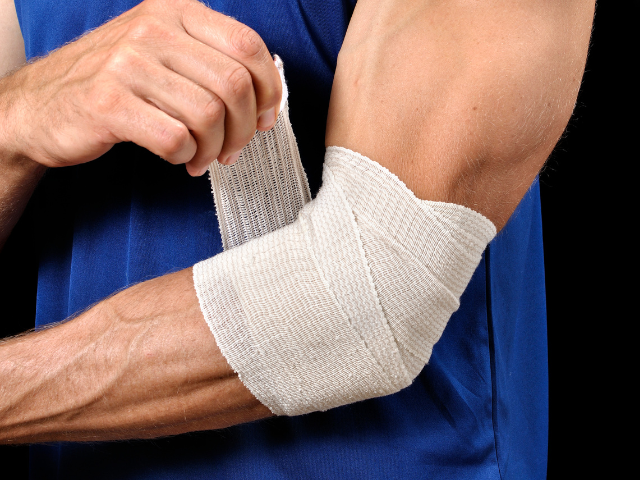 Athlete wrapping a bandage around their injured elbow for support.