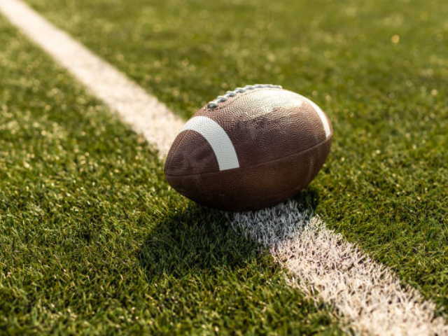 A football placed on a grass field, ready for play.