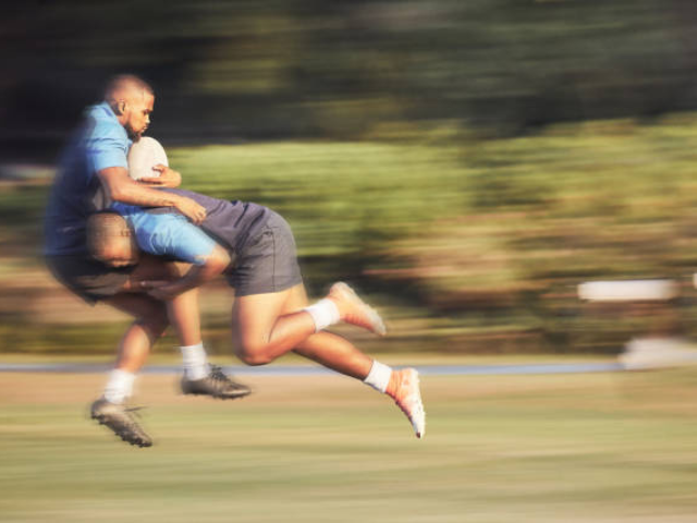 Two rugby players tackling during a fast-paced game.