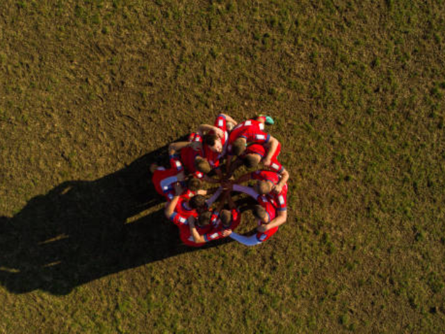 Rugby players huddling in a circle before a game.