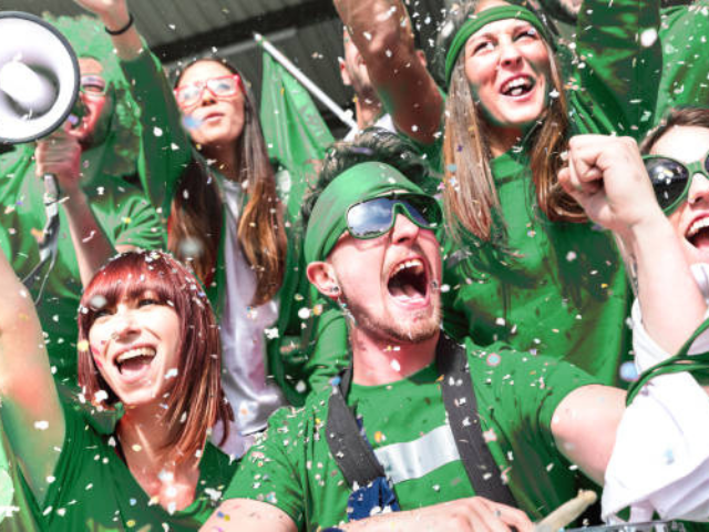 Excited fans cheering at a rugby game.