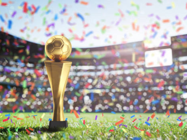 A golden trophy on a field with confetti falling in a stadium