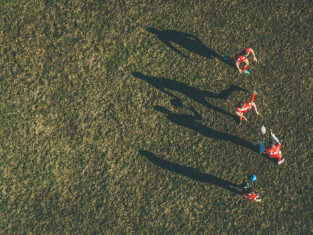 Women rugby players walking on a field at sunset.