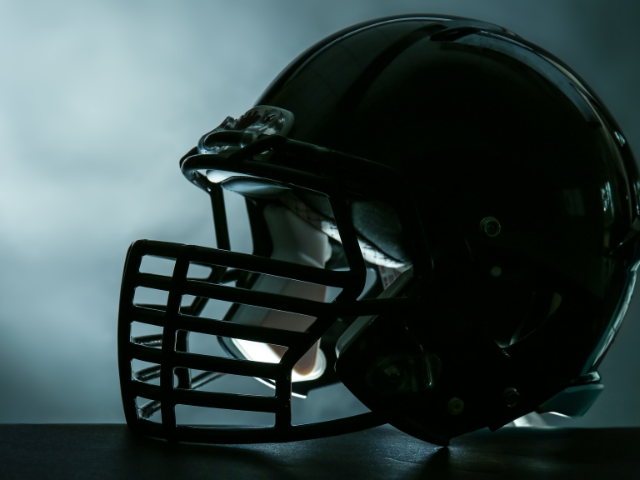 A black football helmet in a dramatic, low-light setting.