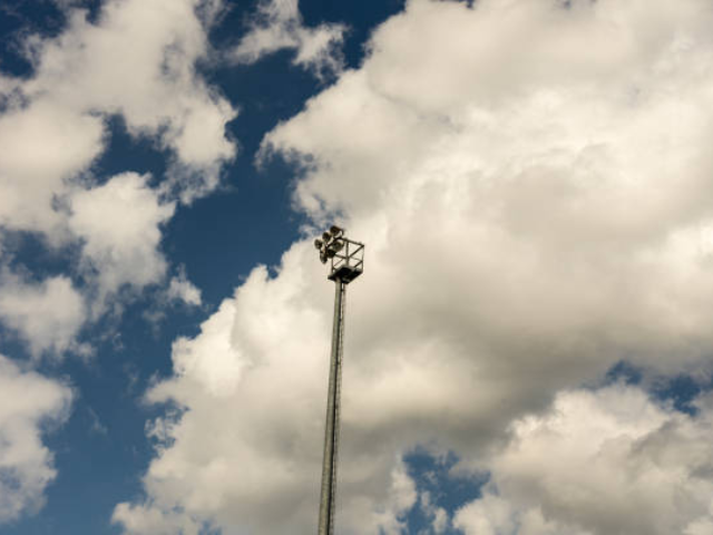 Stadium floodlights with clouds in the background.