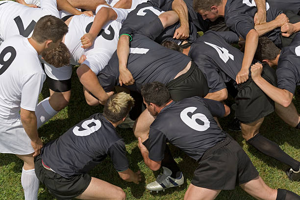 A group of rugby players in black and white jerseys competing in a scrum.