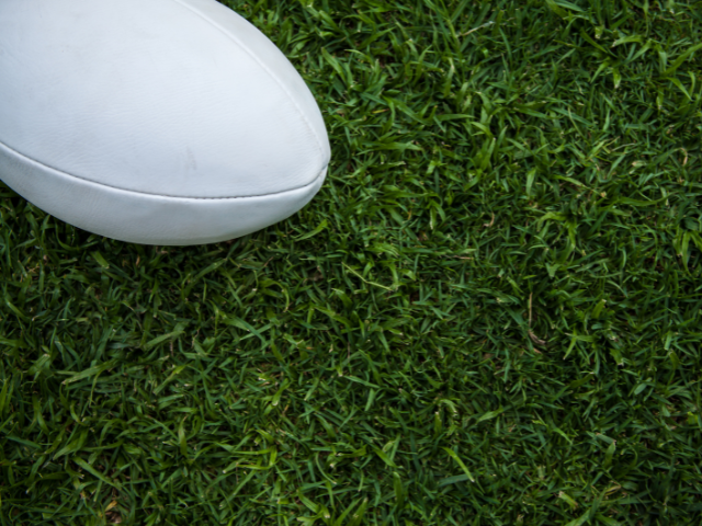 Close-up of a white rugby ball on the grass.