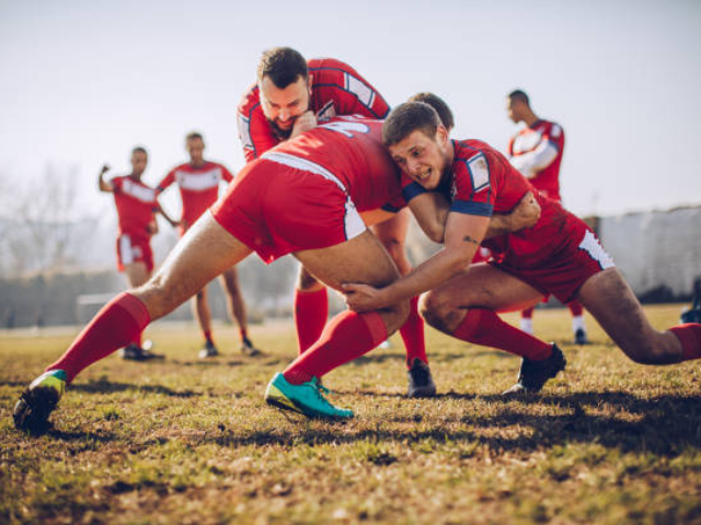 A rugby player being tackled mid-air during a high-speed game.