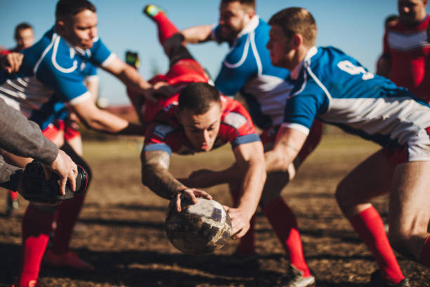 Rugby player diving to score while surrounded by opposing players during a game.