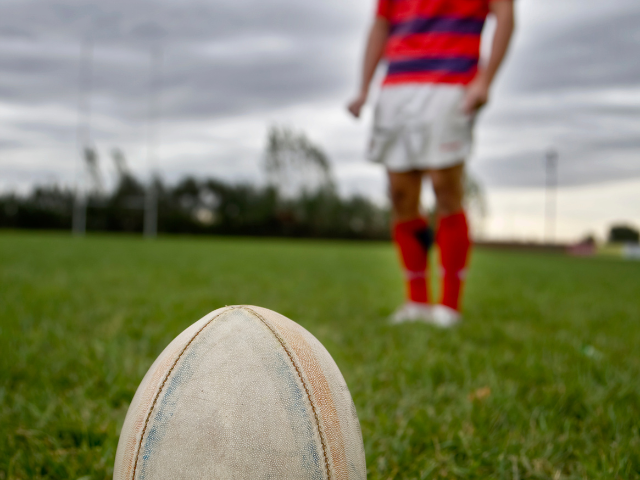 A Rugby ball and a man standing in the field