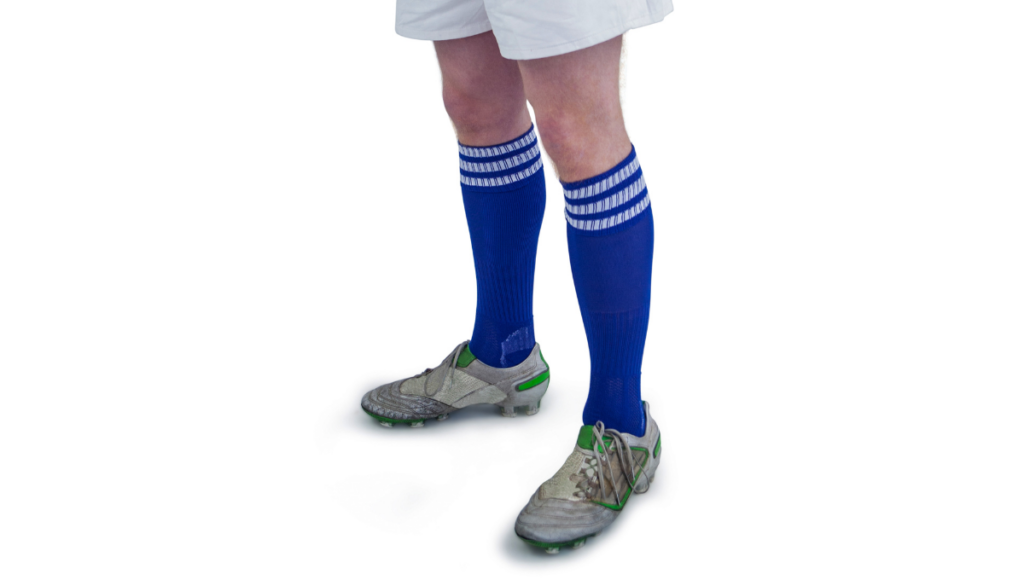 A player standing in rugby gear with royal blue knee-high rugby socks and cleats on a white background, ready for action.