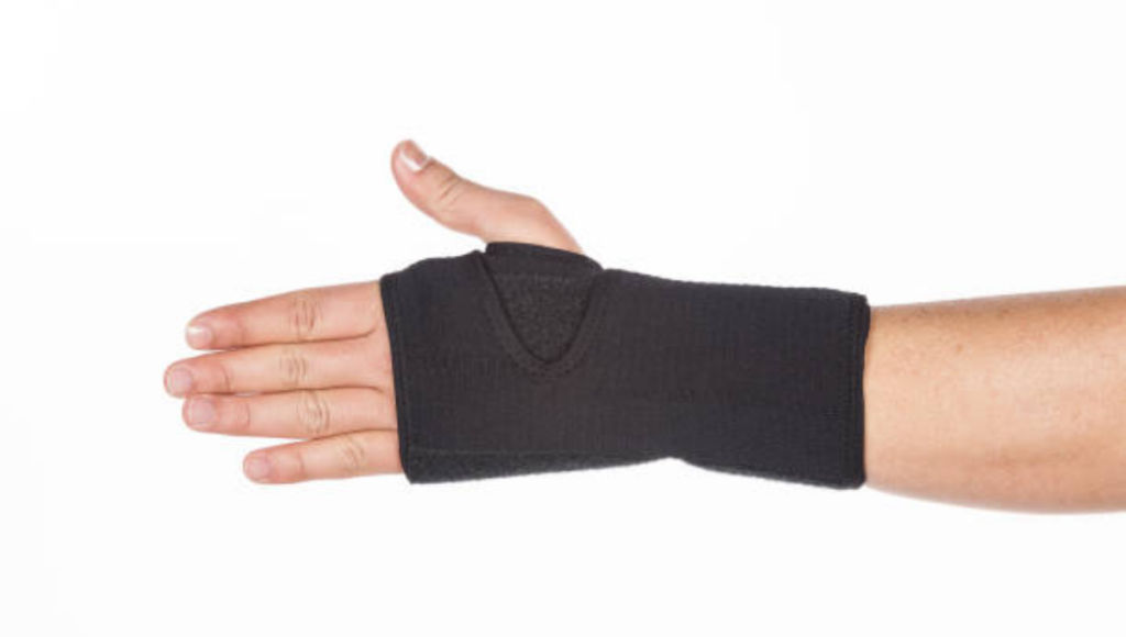 A black wrist brace wrapped around a person's wrist and hand.