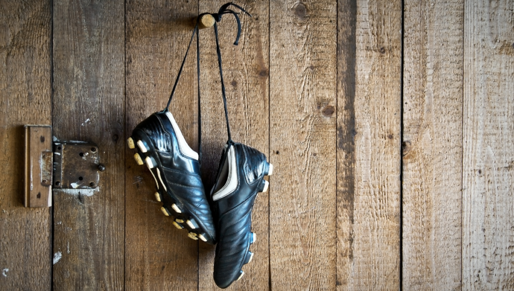 Black rugby boots hanging on a wooden wall, symbolizing the end of a hard day's play.