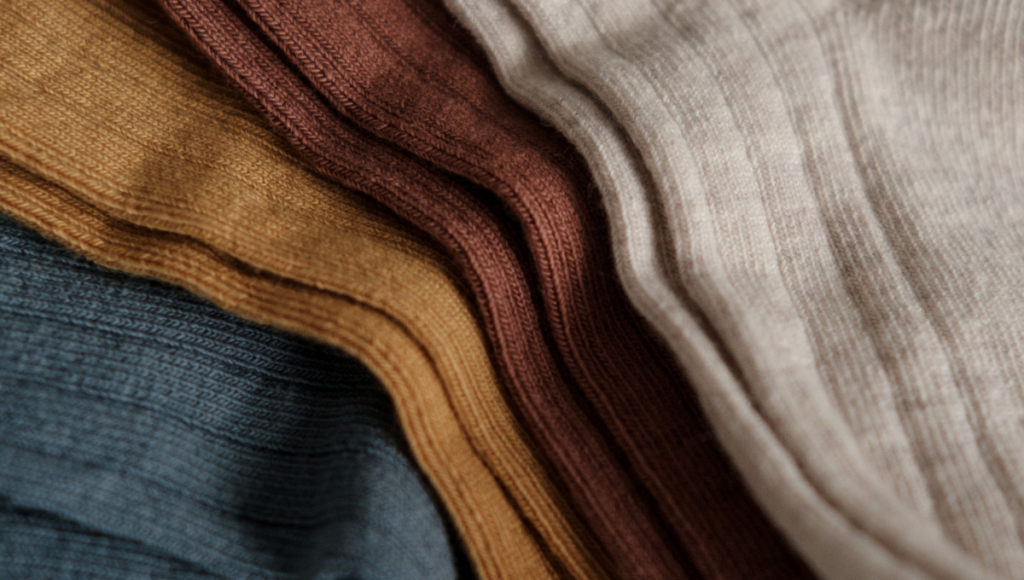 A colorful display of folded socks in muted tones of brown, beige, and blue, showcasing ribbed textures.