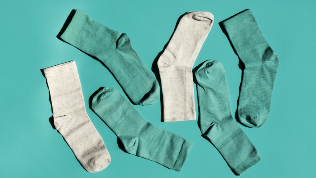 Multiple pairs of green and gray socks neatly arranged on a turquoise background.