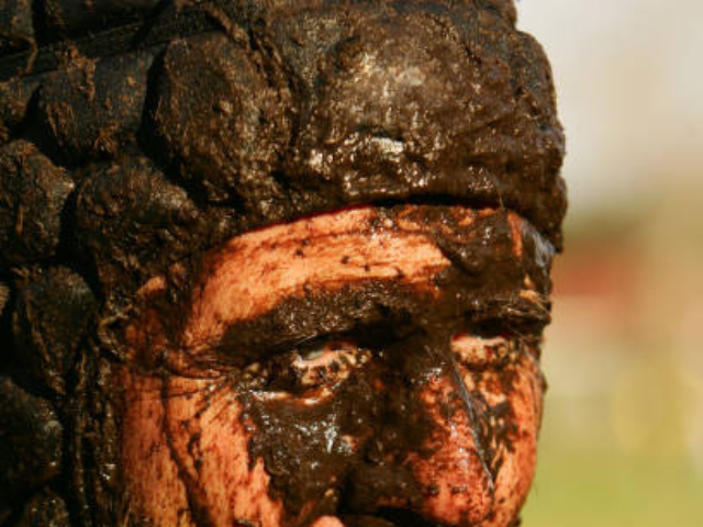 Close-up of a player’s head, covered in mud, with focus on the scrum cap.