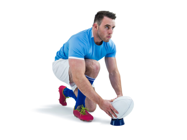 Rugby player crouching to place the ball on a tee before a kick.