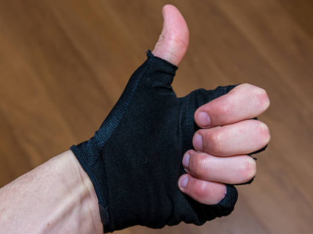 A hand wearing a black fingerless glove giving a thumbs-up gesture.