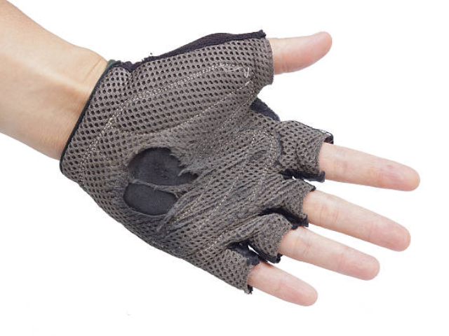 A worn-out fingerless glove made of mesh fabric, showing signs of heavy use with holes and tears.