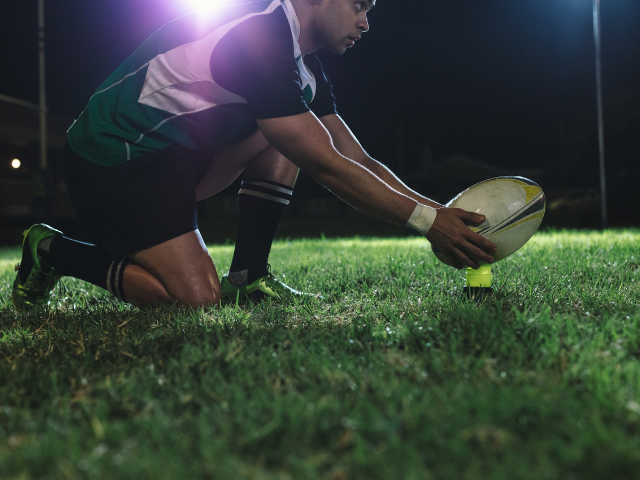 A rugby player placing a rugby ball in the ground