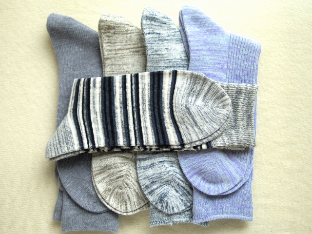 A selection of rugby socks in different colors and patterns, including stripes and solid shades, neatly stacked on a beige background.