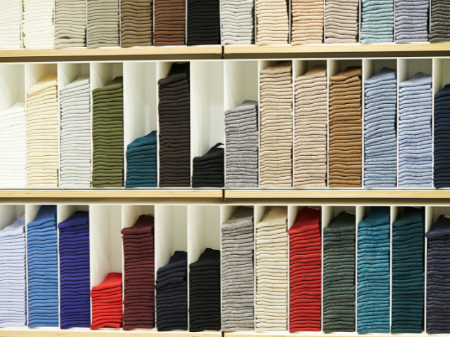 Neatly stacked rows of folded socks of various colors and styles on display shelves.