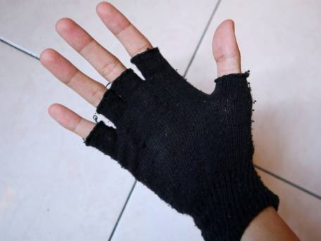 A hand wearing a black fingerless knitted glove.