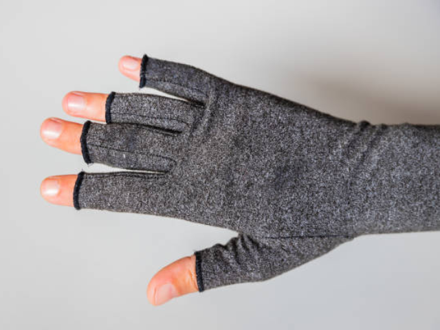 Close-up image of a hand wearing a thin gray fabric fingerless glove with all fingers visible.