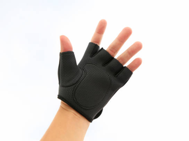 A black, half-finger glove being worn on a person's hand, with the fingers exposed.