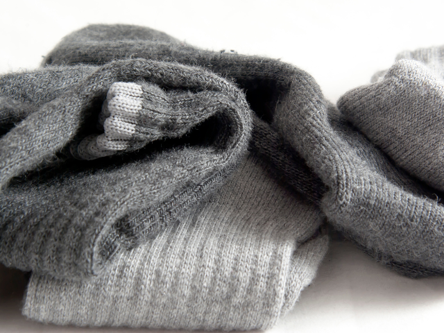 A pile of gray woolen socks, folded neatly on a white background.