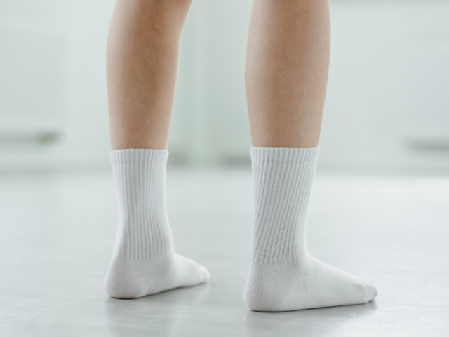 A person wearing white socks standing on a smooth, light-colored floor.