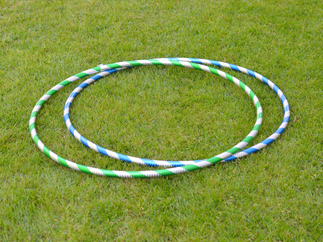 Two colorful hula hoops resting on a grass field, ready for a training or exercise activity.