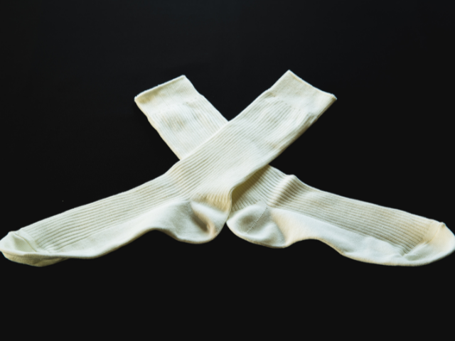 A pair of white socks placed crisscross on a dark background.