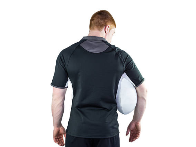 A rear view of a man holding a rugby ball under his arm, wearing a black rugby jersey with light gray details.