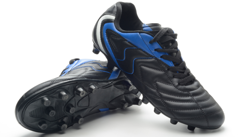 A pair of black and blue rugby boots with black soles.