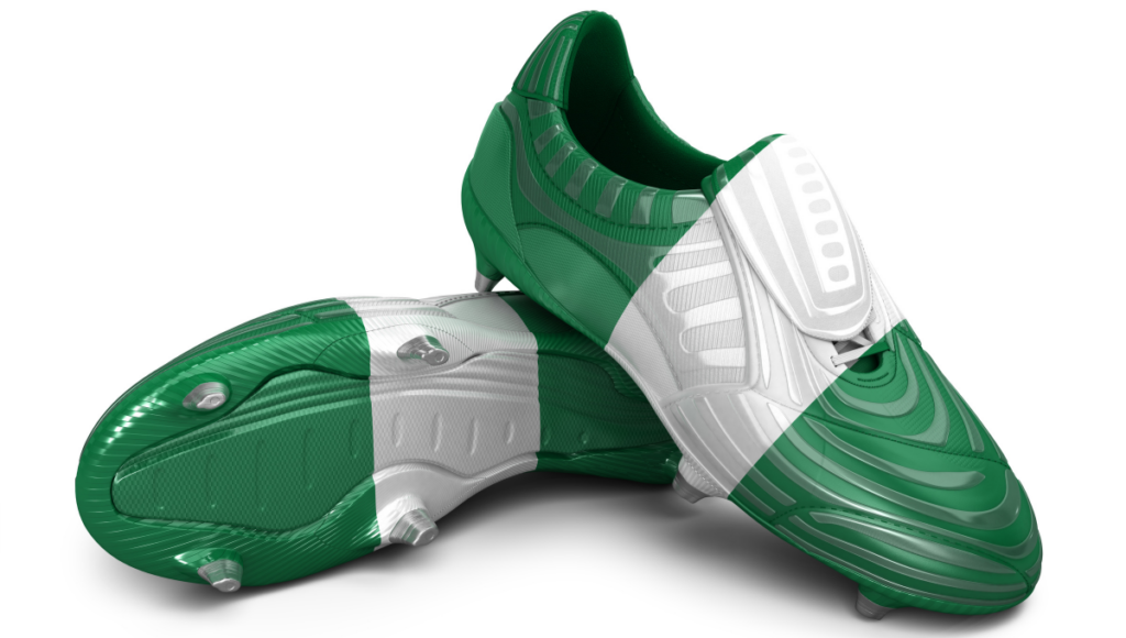 A pair of green and white rugby boots with a sleek, modern design and studded soles.