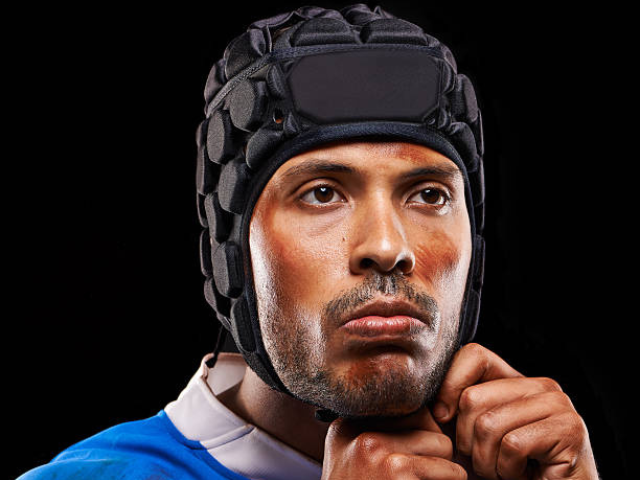 A focused rugby player tightening his scrum cap, ready for action.