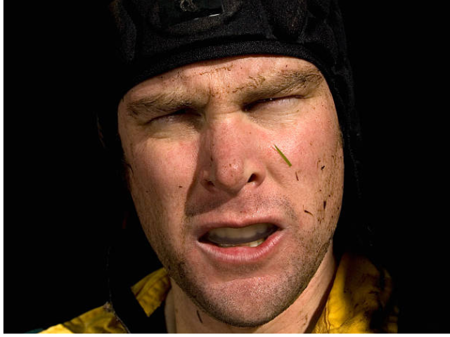 A rugby player wearing a scrum cap, with a fierce expression.