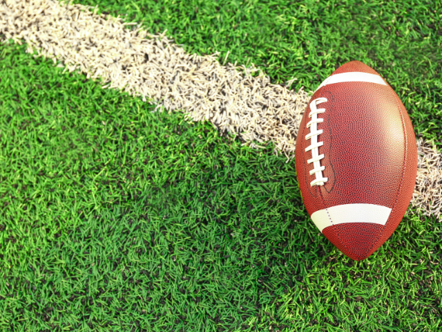 A vintage leather rugby ball on a grass surface.