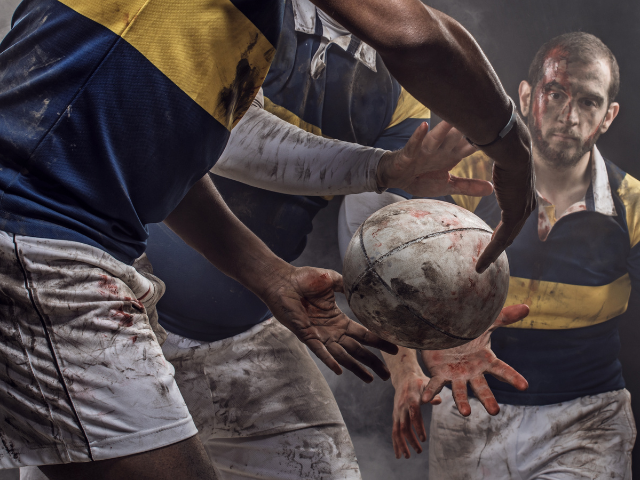 A dramatic shot of rugby players in action, fighting for control of a muddy ball.