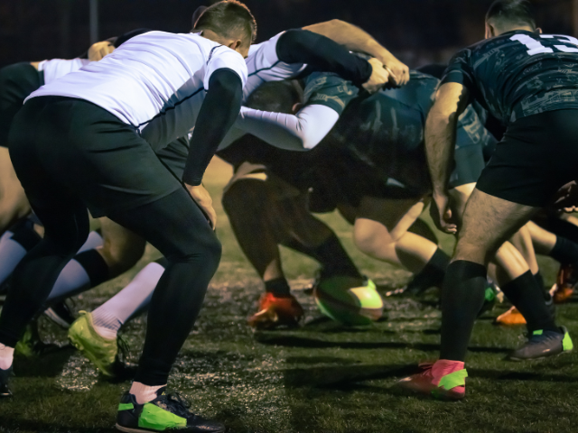 Rugby players engaging in a scrum during a night match.