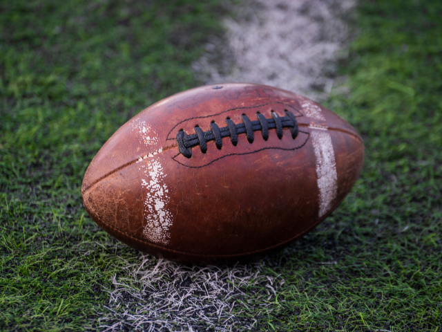 A worn-out rugby ball resting on the field.