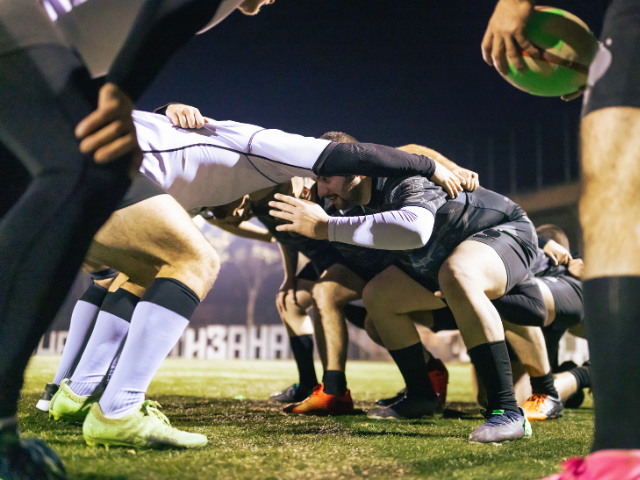 Players crouched and locked in a scrum, battling for possession.